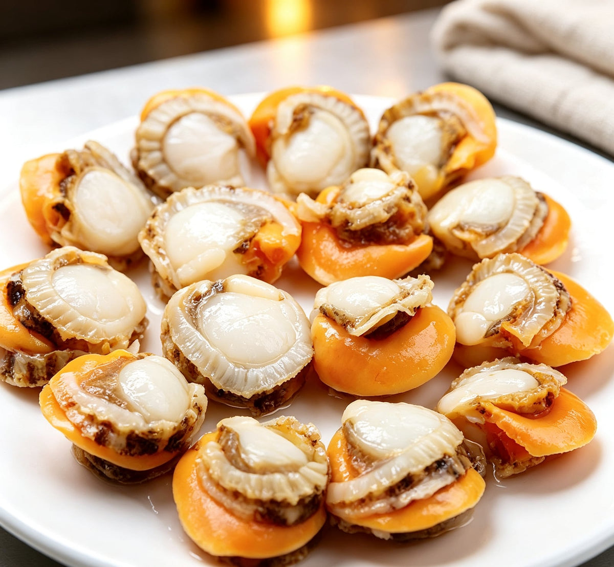 Fresh half-shell scallops with orange roe on a white plate