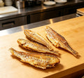 Golden pan-fried yellow croaker fish on a wooden board